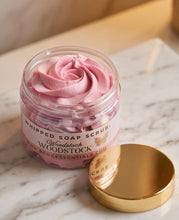 Pink whipped soap scrub in a clear jar with a white label reading Woodstock Woodstock, shown on a marble surface with a gold lid beside it.
