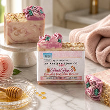 Decorative soap with floral design and a box labeled 'Pink Rose & Orange Blossom Honey' on a white background.