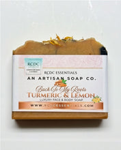 A rectangular bar of RCDC Essentials Turmeric & Lemon luxury face and body soap, wrapped in a white paper label with pink and orange accents, set against a plain white background.