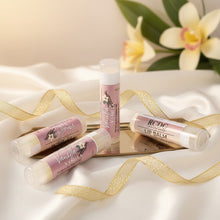 Three lip balms with visible branding on a white surface with gold ribbons and flowers in the background. Vanilla flavor by RCDCessentials