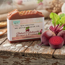 A bar of RDCC Essentials Beetroot & Buttermilk soap displayed on a rustic wooden surface with its paper packaging box, alongside fresh beetroots, a cut beetroot slice, and green leaves.
