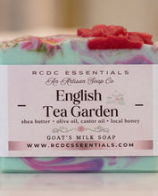 A close-up of a bar of RCDC Essentials 'English Tea Garden' goat's milk soap. The soap features a light teal and pink marbled base with a textured, rose-pink floral design on top and along the bottom edge.