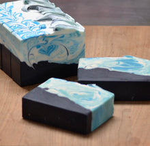 Three bars of soap with blue and white marbled pattern on a wooden surface