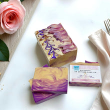 Handmade soap bars with a decorative design on a white surface with a pink rose.