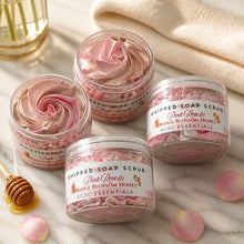 Jars of pink rose and orange blossom honey whipped soap scrub with a plant and flowers in the background.