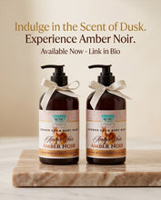 Two amber shower cell and body wash bottles with pump dispensers, tied with white ribbon bows, displayed on a marble slab against a warm beige background with promotional text at the top.