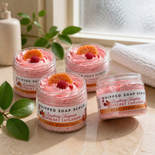Jars of Raspberry Tangerine Whipped Soap Sugar Scrub with pink and orange hues, displayed alongside yellow tulips and decorative fruits on a white background.