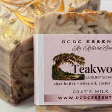 A close-up of a bar of RCDC Essence Teakwood Luxury Soap with a pink label, placed in front of another swirled soap bar with gold leaf detailing on a light marble surface.