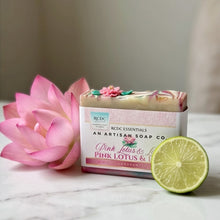 A bar of soap in a white and pink box labeled 'Pink Lotus & Lime' by Redc Essentials, styled on a marble surface with a pink lotus flower and a lime slice.