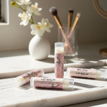 RCDCessentials Vanilla lip balms on a marble surface with flowers and brushes in the background