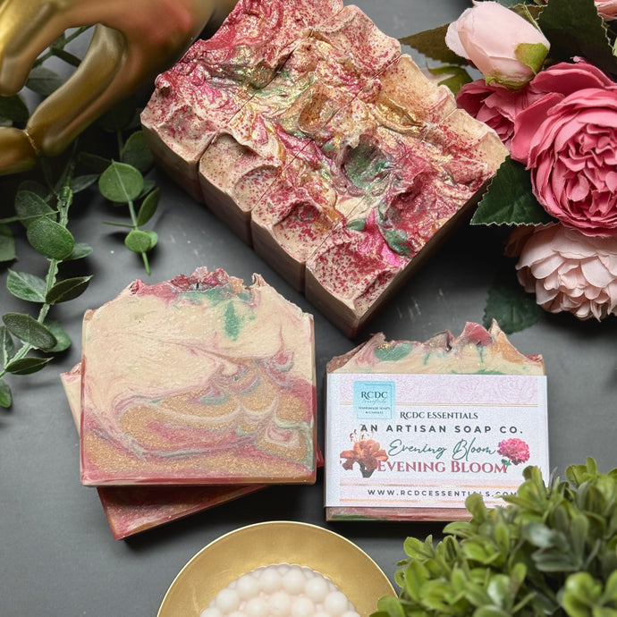 Artisan soap with floral design and packaging on a dark surface with flowers and greenery.