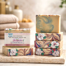 Stack of floral soap bars with RDC Essentials packaging on a wooden surface.