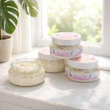 Jars of body butter on a windowsill with natural light and a plant in the background