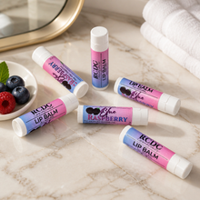 Multiple lip balms with berry flavors on a marble surface.